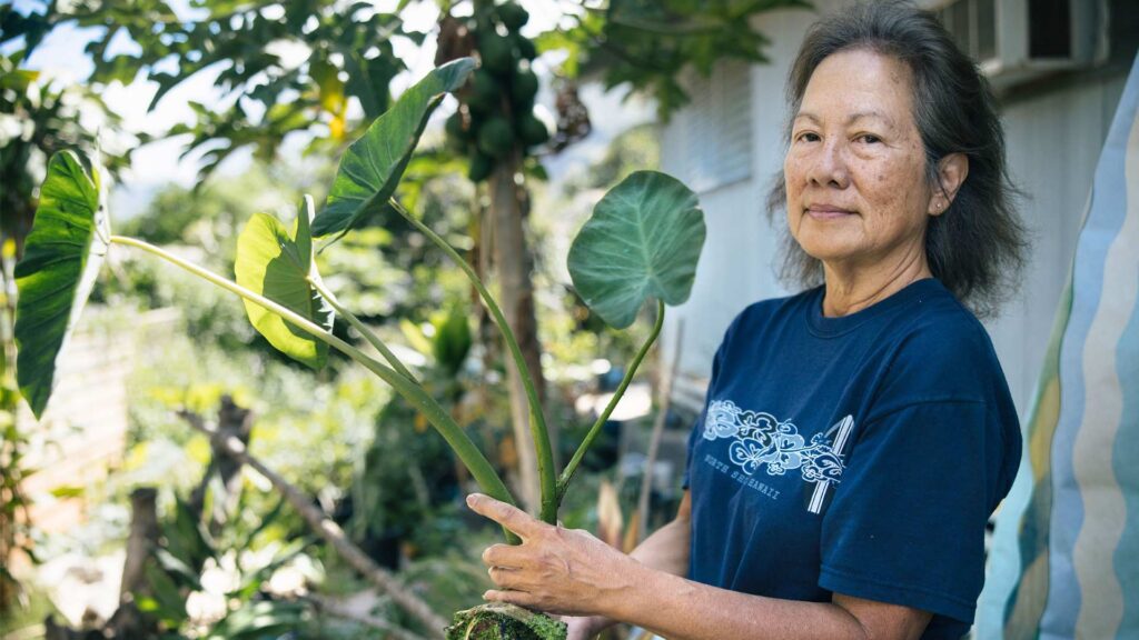 Alyson holding kalo in her garden.