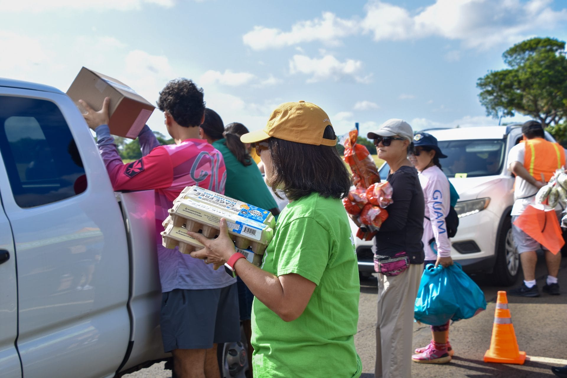 Volunteers loading vehicles with food boxes, eggs, produce, and bread.